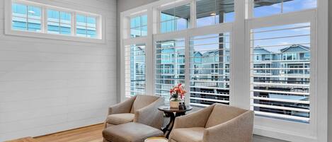 A modern living room with large windows, a sofa, a coffee table, and a rug.