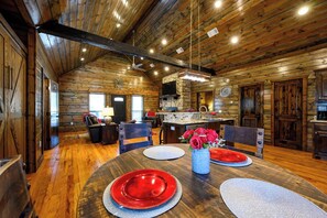 A wooden interior with a dining table set for two, a kitchen area, and a fireplace. - Pond Lily Creek - spacious couples cabin - hot tub (Broken Bow)
