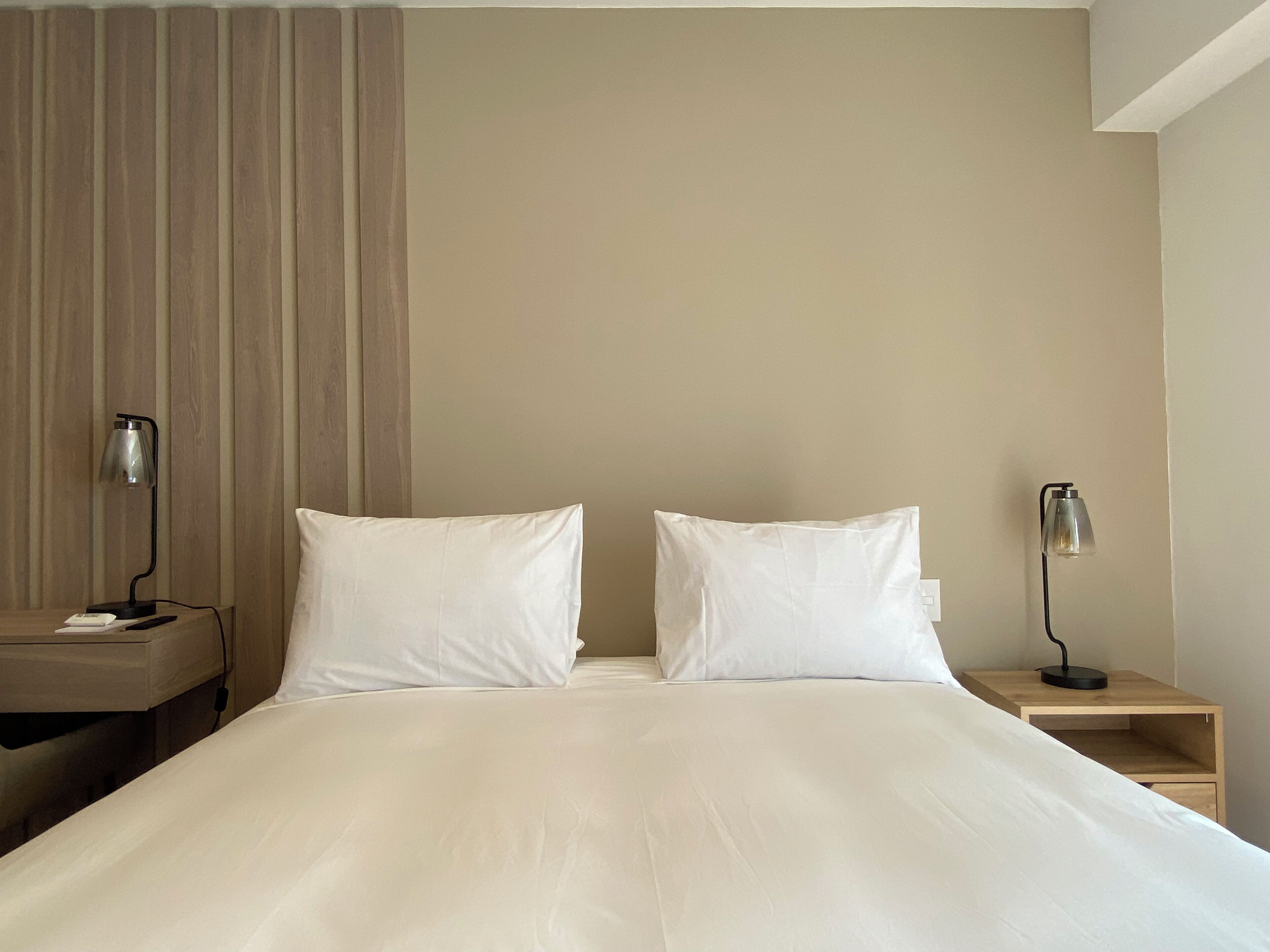 A hotel room with a bed, two bedside tables, and two lamps.