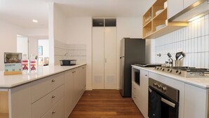 Eine moderne Küche mit einer zentralen Kochinsel, einem eingebauten Backofen und Edelstahlgeräten.