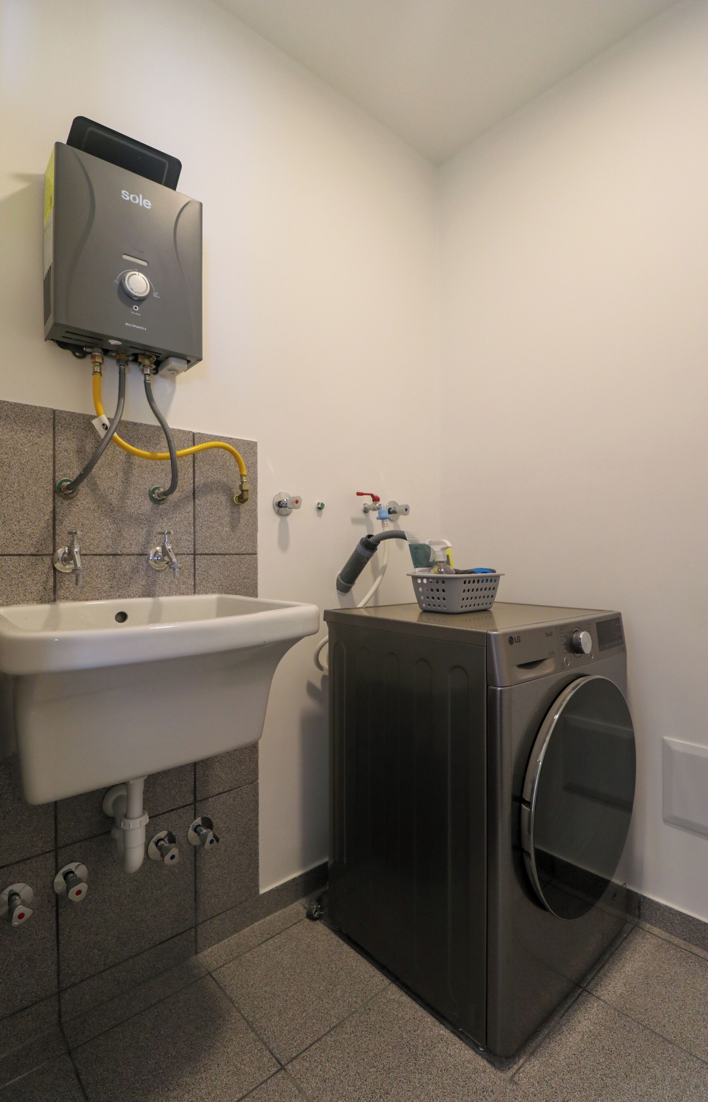 A laundry area with a washing machine, a sink, and a water heater.