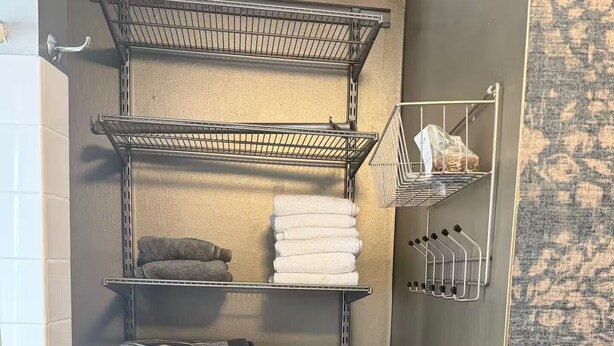 Un bany amb un moble prestatge metàllic integrat que conté tovalloles i productes de tocador.