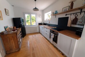 A kitchen with wooden cabinets, a black refrigerator, a wooden countertop, and a window with a view of greenery. - Your base camp on the Côte de Granit Rose near the GR34. (Trélévern)