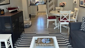 Een moderne woonkamer met een zwart-wit streepig vloerkleed, een witte salontafel met een boek getiteld 'The Ferrari Book', en een grijze bank.