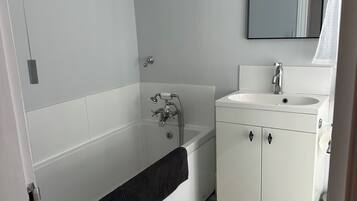 Un baño con bañera, lavabo y espejo.