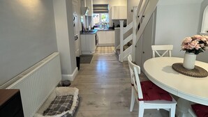 Een moderne keuken met witte kasten, een centraal eiland en een eethoek met een ronde tafel en stoelen.