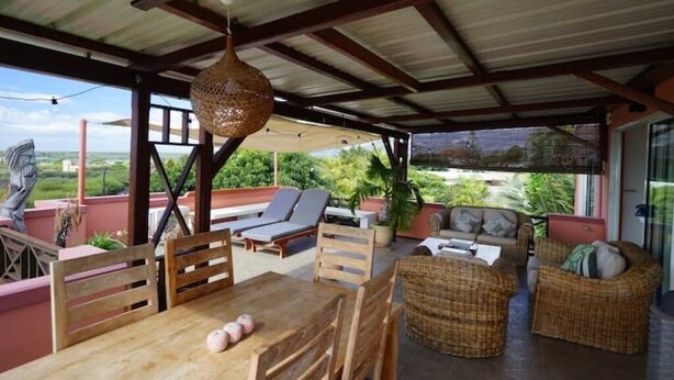 Un espacio de estar al aire libre cubierto con muebles de madera, una lámpara colgante y vistas al paisaje.