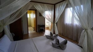 Un dormitorio con cama, cortinas blancas y vistas al exterior.
