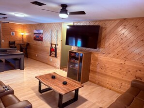 Ein Zimmer mit Billardtisch, flachbildfernseher an der Wand und einer Wand mit Ziegelsteinmuster.