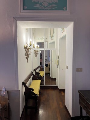 A hallway with a wooden bench, a mirror, and a chandelier. - AMAZING TRASTEVERE (Roma)