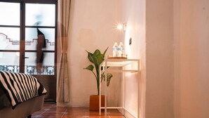 Een kamer met een bank, een potplant, een klein tafeltje met flessen en uitzicht op een trap.