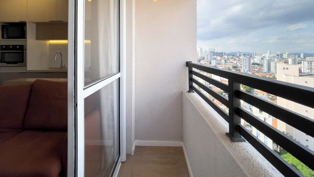 Un balcon avec vue sur la ville, un coin cuisine équipé d’appareils modernes et un espace salon confortable.