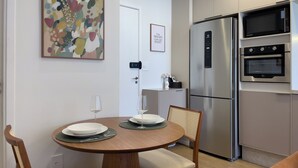 Une cuisine moderne équipée d’un réfrigérateur en acier inoxydable, d’un four double et d’un four à micro-ondes. On y trouve une table à manger avec des assiettes et des verres à vin.