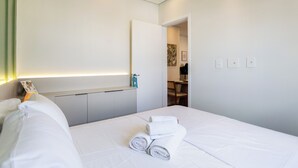 Une chambre d’hôtel avec un lit bien fait, une table de chevet, un bureau et une chaise.