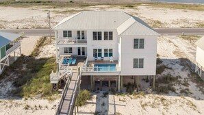 Una casa frente al mar de dos pisos con piscina, un porche cubierto y vista al océano.