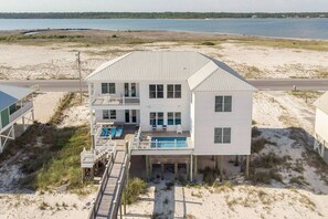A two-story beachfront house with a swimming pool, a covered deck, and a view of the ocean. - Luxury Beachfront House w/pool on Private Beach (Gulf Shores)