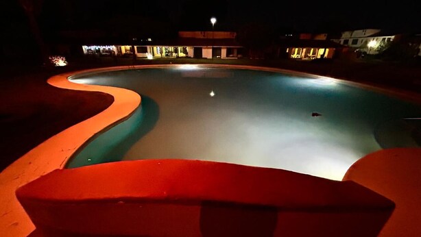 A swimming pool at night with a curved edge and a red border. - Cuernavaca In Sumiya San José: dream garden. (Jiutepec)