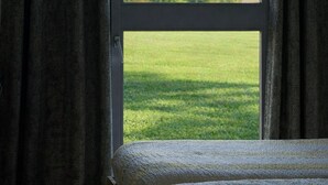 A room with a large window, a bed, and curtains.