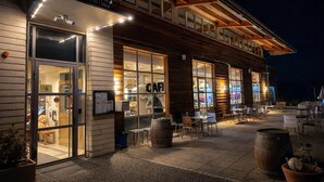 A cozy outdoor cafe with wooden exterior and large windows, featuring outdoor seating and a rustic ambiance.