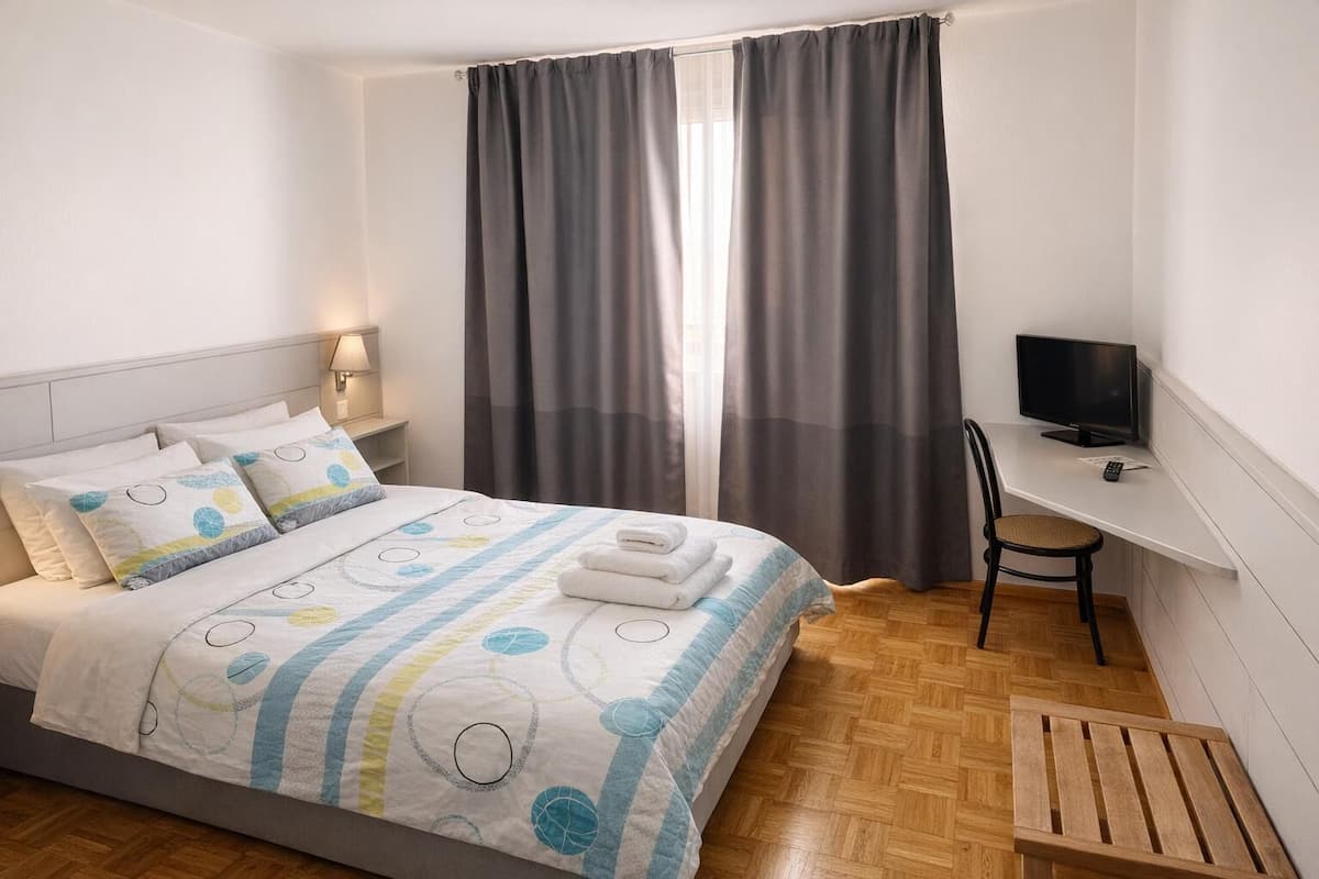 Une chambre à coucher avec un lit, un bureau avec une télévision et une chaise.