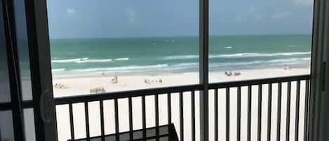 Vue sur une plage depuis une chambre dotée d’un balcon, avec une rambarde et une chaise.