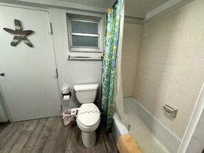 A bathroom with a toilet, a window, a shower curtain, and a bathtub. - Beach Pool Open Direct Beachfront Condo Sunsets (Siesta Key)