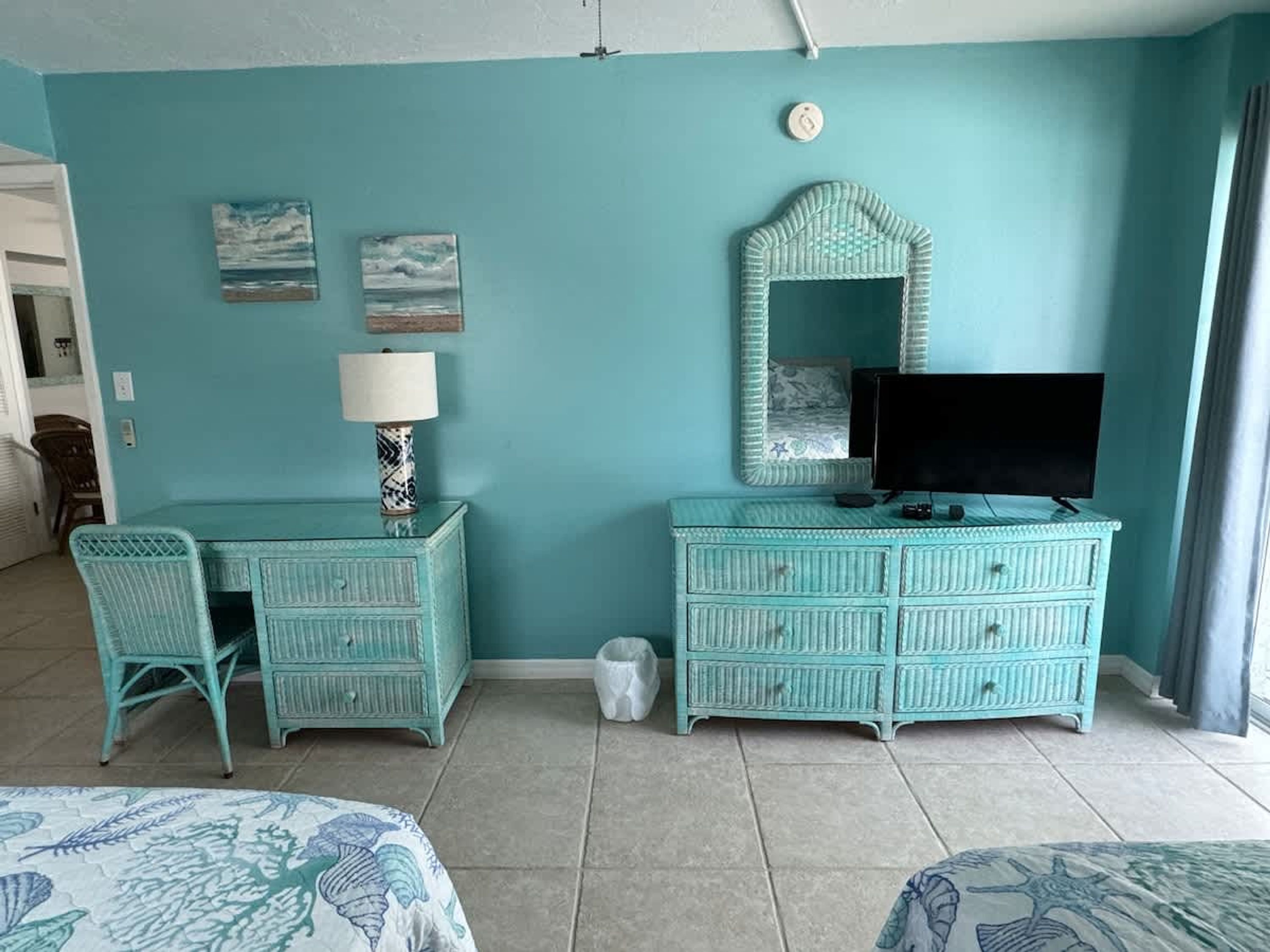 A room with teal walls, a television, a dresser, a chair, and a bed.
