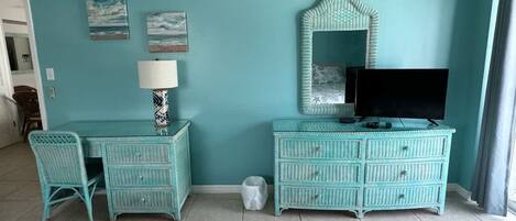 A room with teal walls, a television, a dresser, a chair, and a bed.