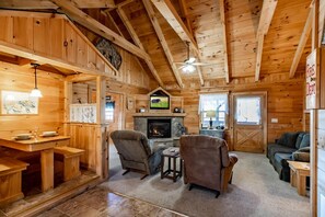 A cozy cabin interior with a stone fireplace, wooden furniture, and a television. - Amazing Views Hot Tub Pool Table Fireplace Relax (Gatlinburg)