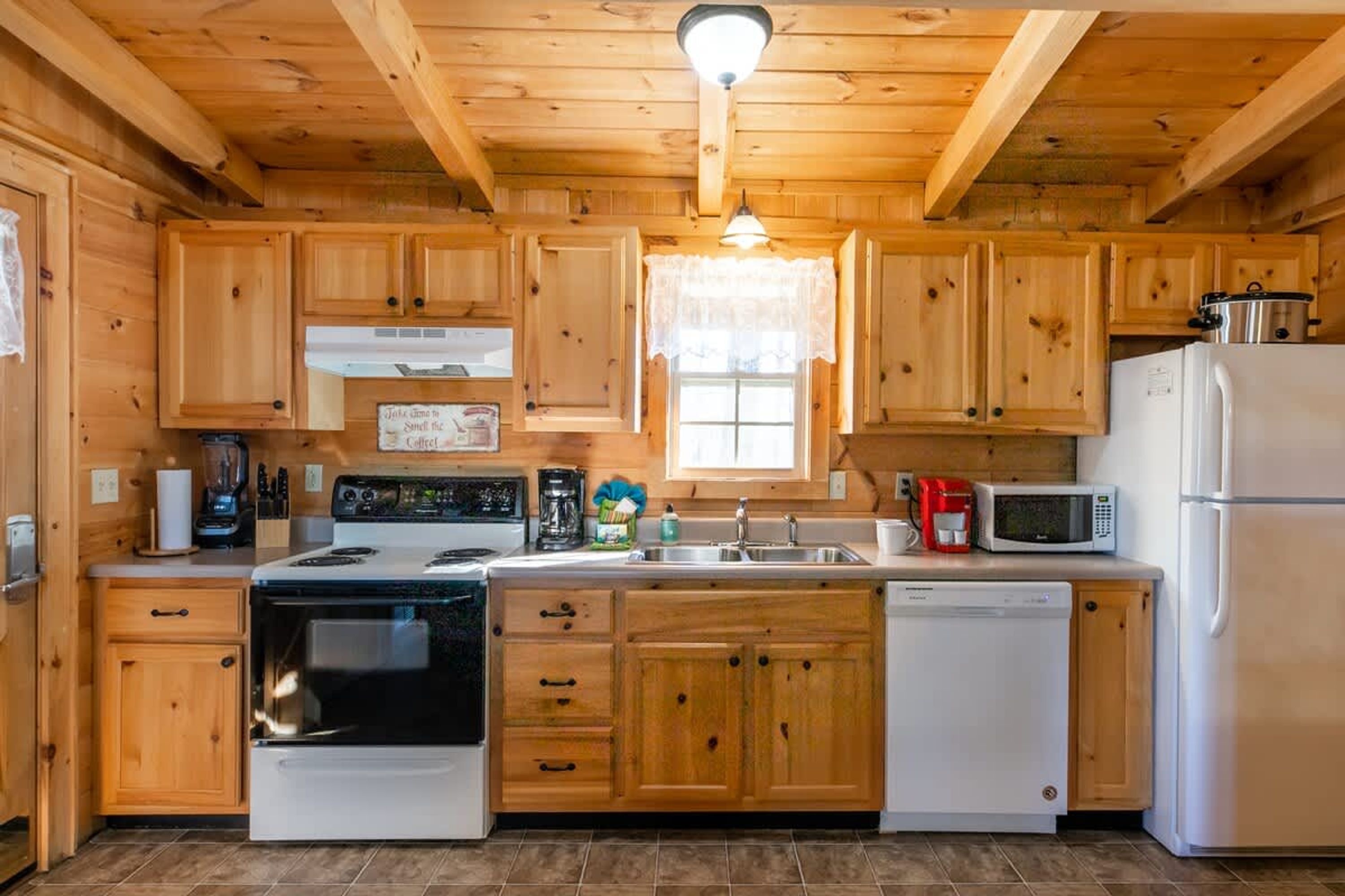 Una cocina con armarios de madera, estufa, lavavajillas, microondas y refrigerador.