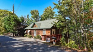 A rustic building with a green roof, a wooden porch, and a signboard. - Greatview Pooltable Hottub Privacy Fireplace (Sevierville)