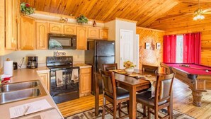 A wooden cabin interior with a kitchen, dining area, and pool table. - Greatview Pooltable Hottub Privacy Fireplace (Sevierville)
