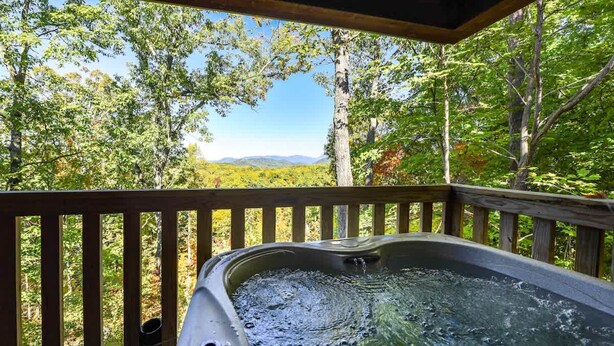 A hot tub on a wooden deck with a view of a forest and mountains. - Greatview Pooltable Hottub Privacy Fireplace (Sevierville)
