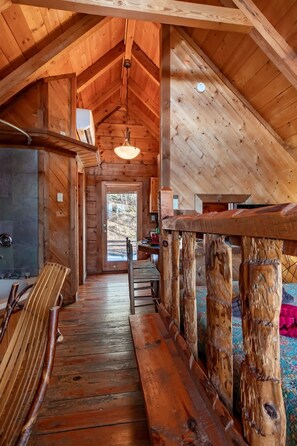 A rustic wooden interior with a high ceiling, a fireplace, and a view of the outdoors. - Cute Studio Cabin Views Private Hot Tub Relax (Sevierville)