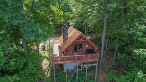 Eine Holzhütte mit einer Holzdielen-Terrasse und einem Steinkamin, umgeben von dichtem Wald.