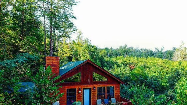 A rustic cabin with a wooden exterior, a chimney, and a porch with chairs. - Secluded Cabin Near Smoky Mountains Hot Tub Honeymoon (Sevierville)