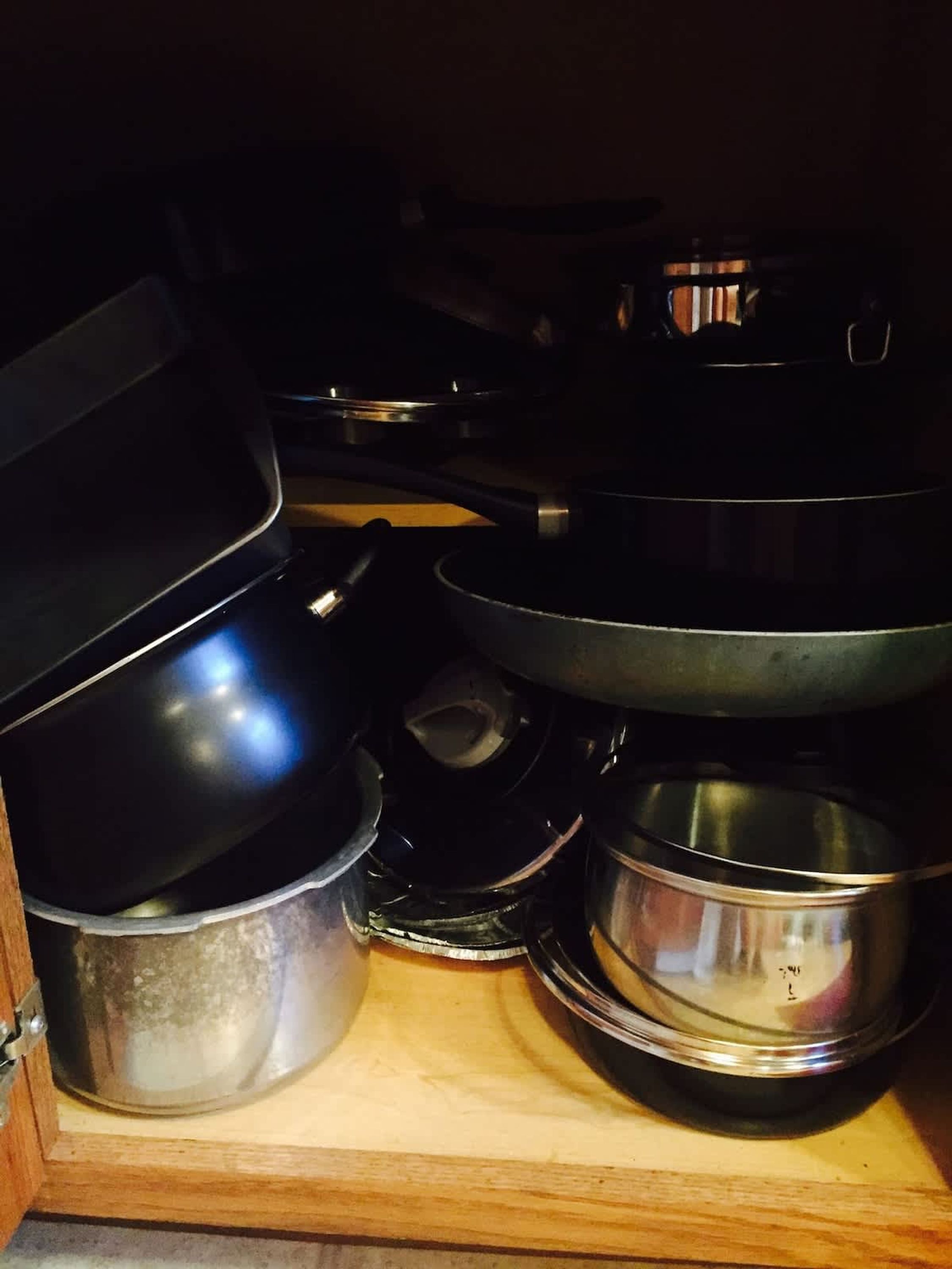 Ett köksskåp med olika kastruller och stekpannor.