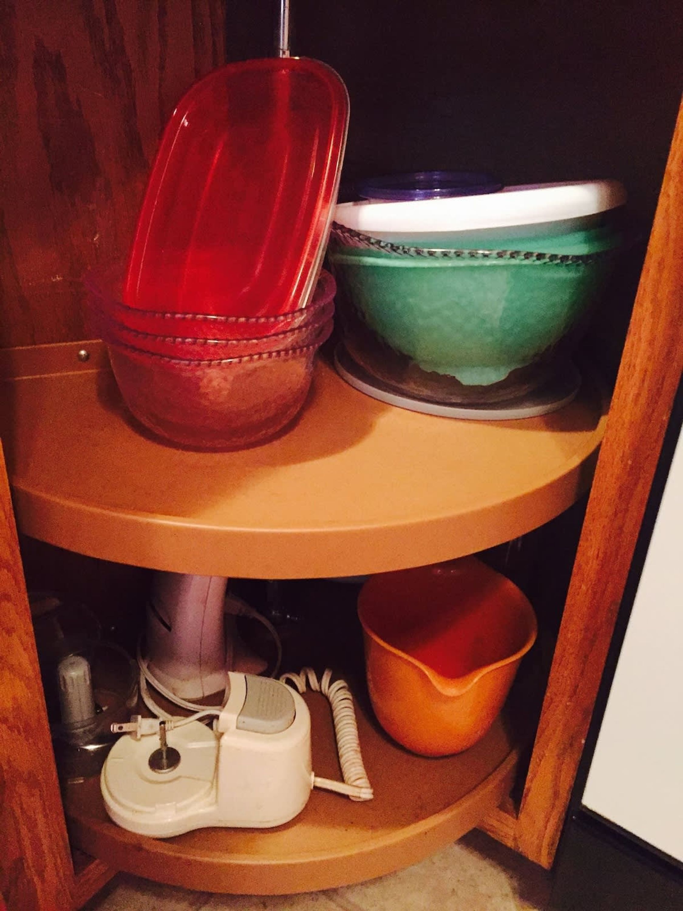 A wooden shelf with stacked dishes and a toilet brush.