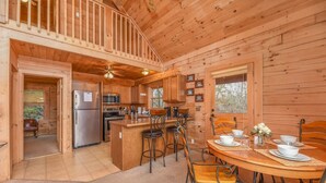Una cabaña de madera con cocina, comedor y un balcón.