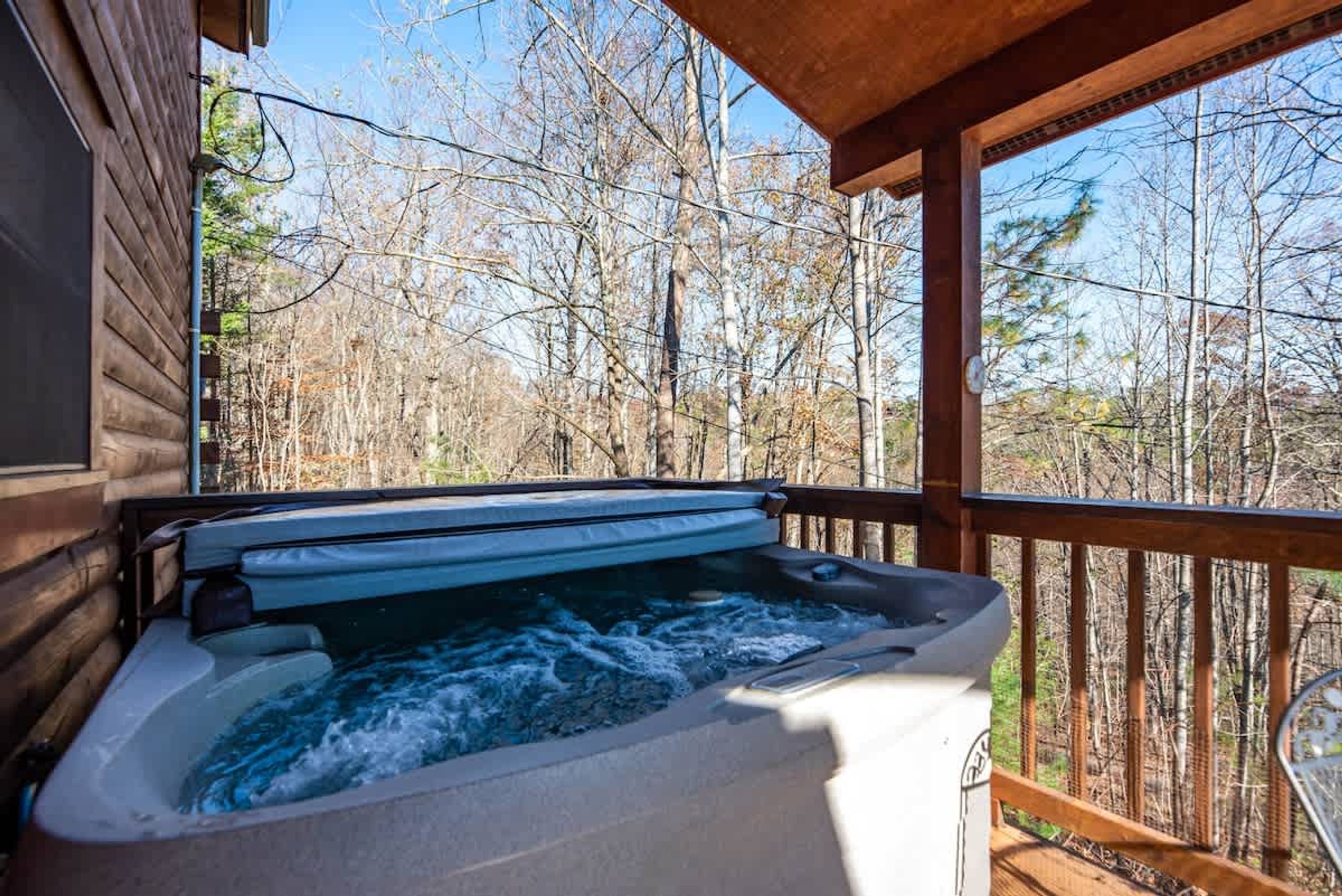 Un jacuzzi en una terraza de madera con vista a un bosque.