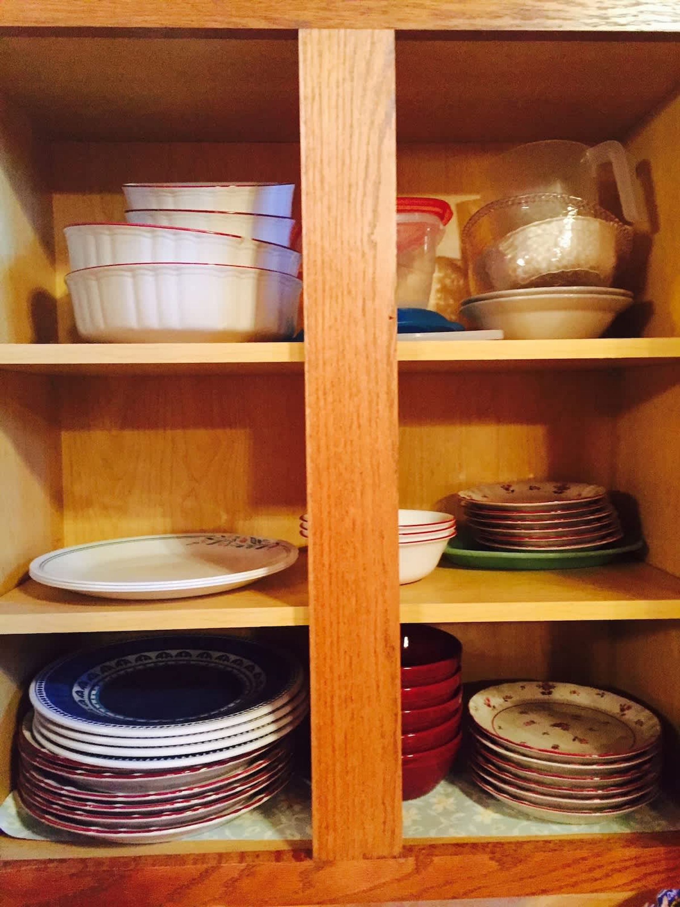 Une étagère en bois, dotée de plusieurs compartiments, où sont rangées des piles d’assiettes et de bols.