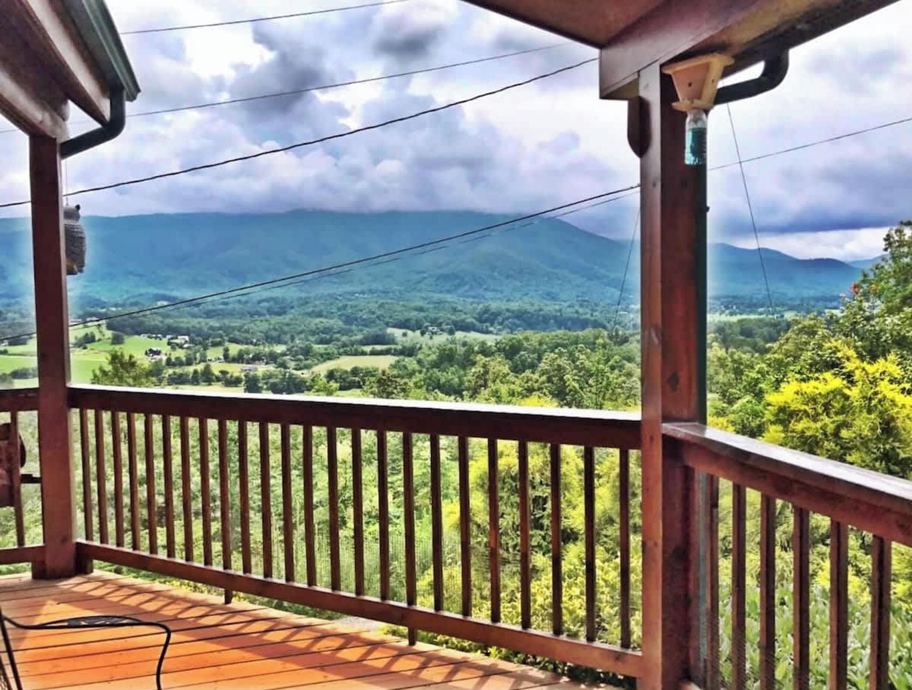 A wooden deck with a view of a green landscape and mountains.