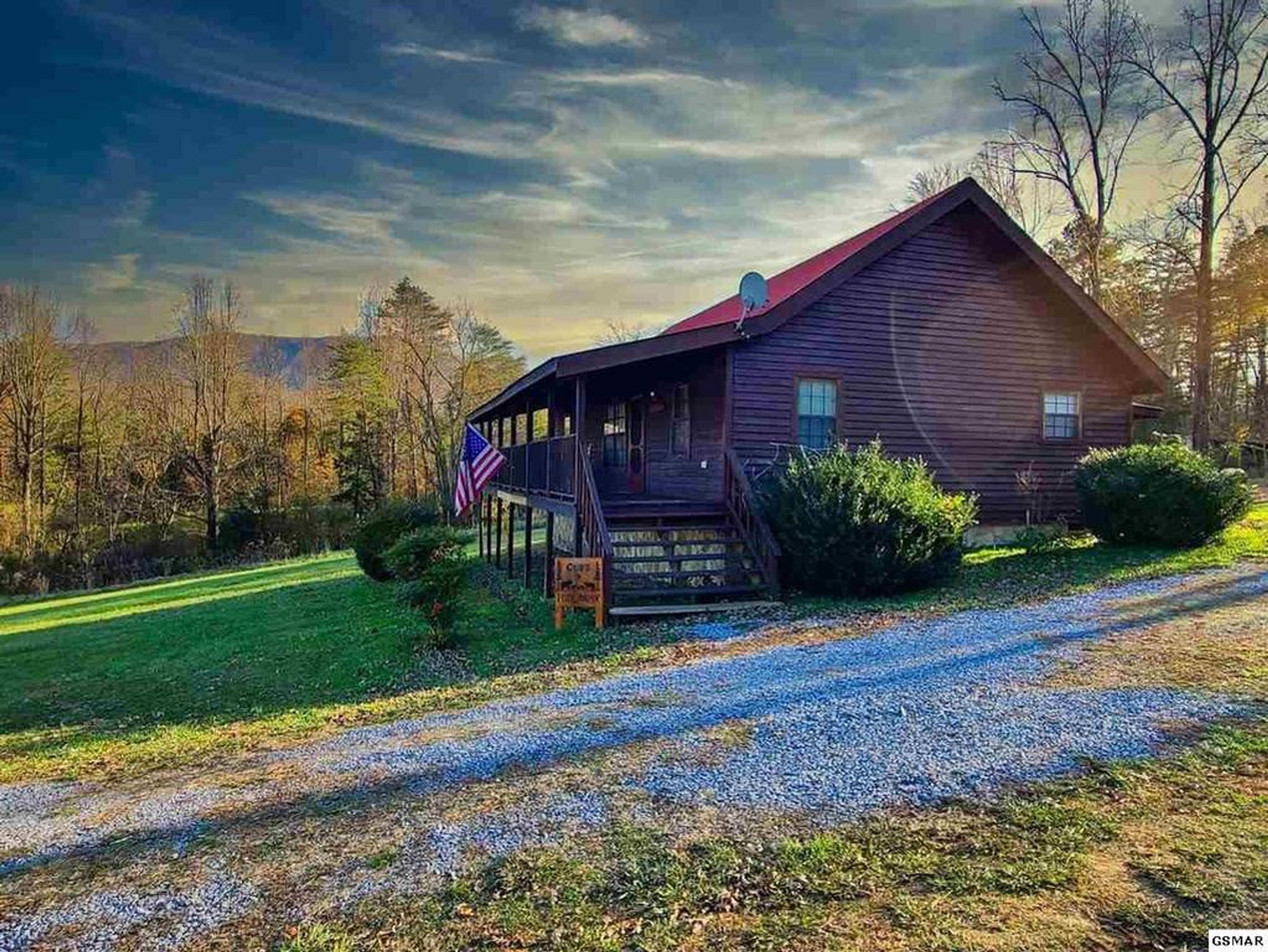 Un chalet rustique doté d’une véranda, entouré d’un paysage verdoyant et d’arbres.
