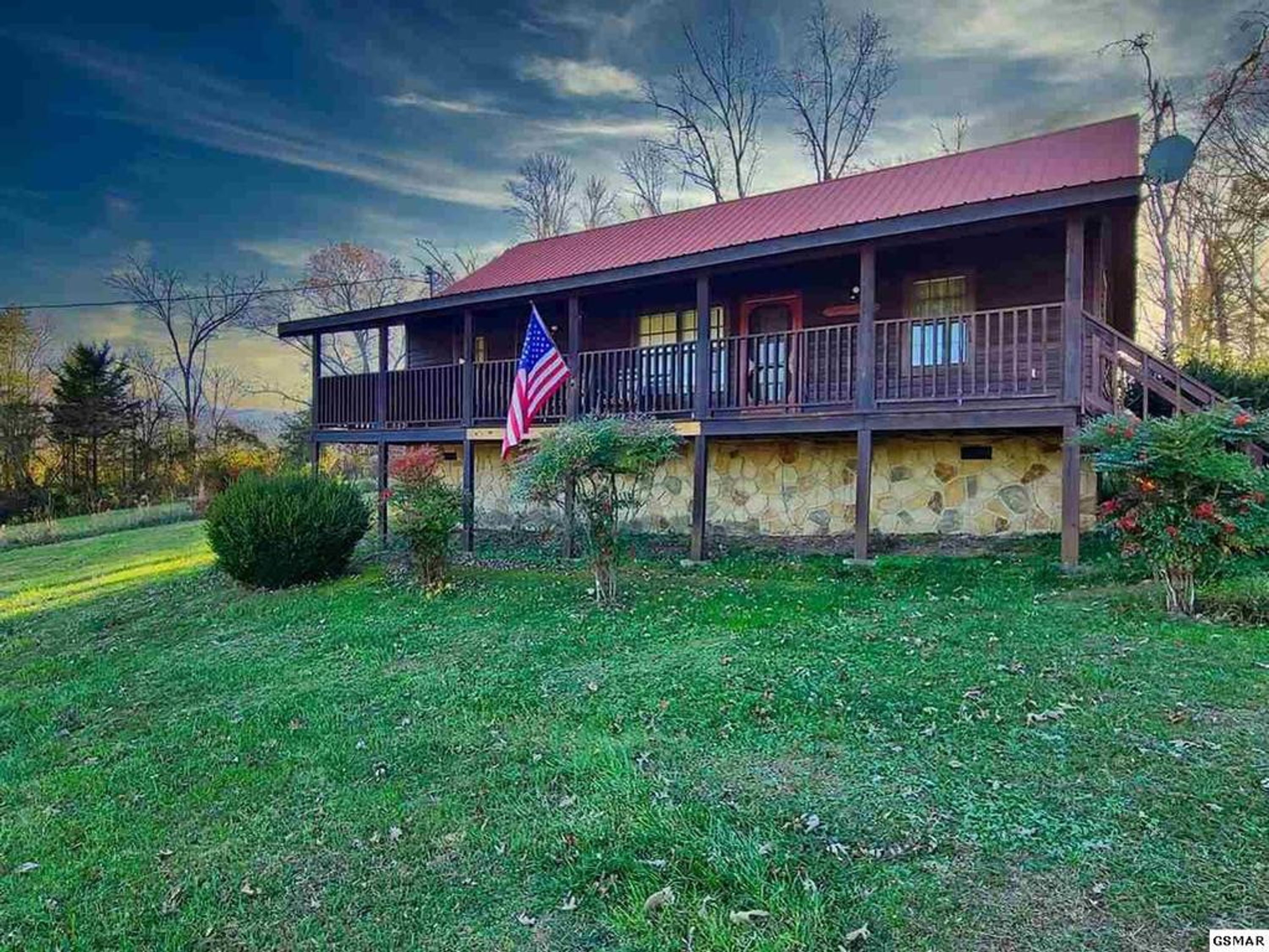 A two-story house with a stone foundation and a red roof.