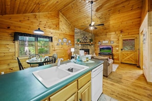 A cozy cabin interior with a wooden interior, a dining area, a kitchen with a large island, and a fireplace. - Location Log Cabin Hot Tub Fireplace Pool Fishing (Sevierville)