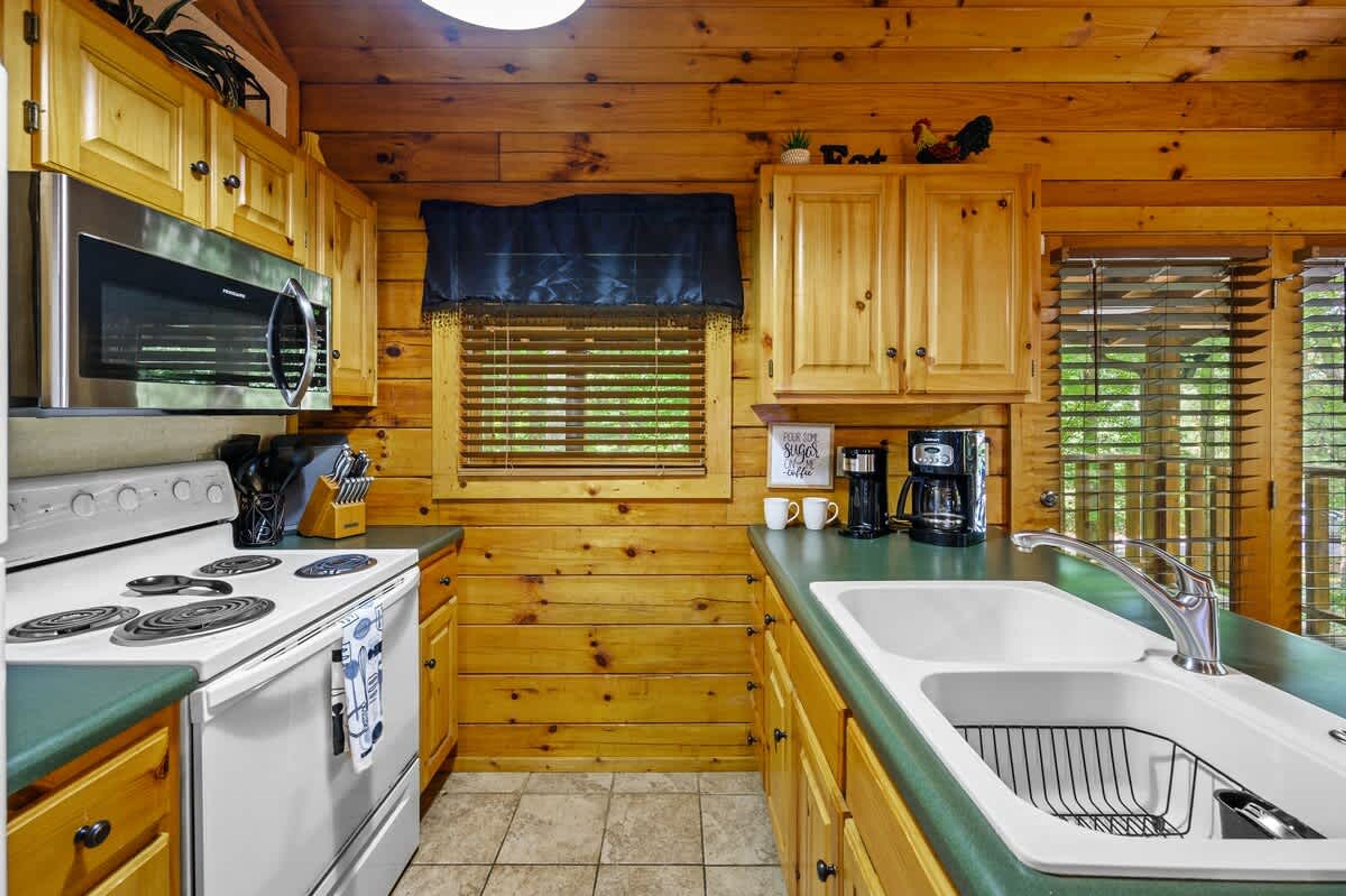 Una cocina con armarios de madera, estufa, microondas y pileta.