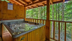 A wooden cabin with a hot tub and a view of the forest. - Location Log Cabin Hot Tub Fireplace Pool Fishing (Sevierville)