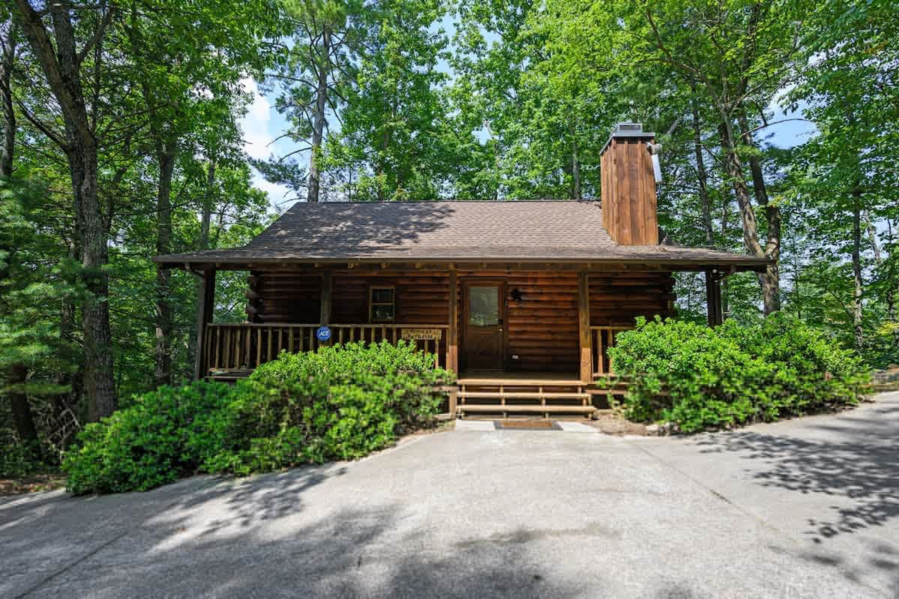 A rustic cabin with a wooden exterior, a chimney, and a porch with steps leading to the entrance.