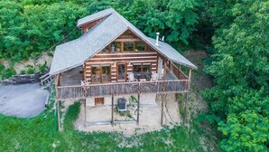 A log cabin with a balcony, surrounded by dense forest. - View Private Hot Tub Pool Table Fireplace Relax (Sevierville)