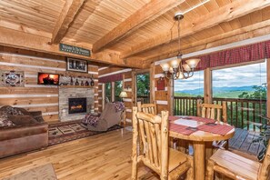 A cozy cabin interior with a fireplace, wooden furniture, and a scenic outdoor view. - View Private Hot Tub Pool Table Fireplace Relax (Sevierville)